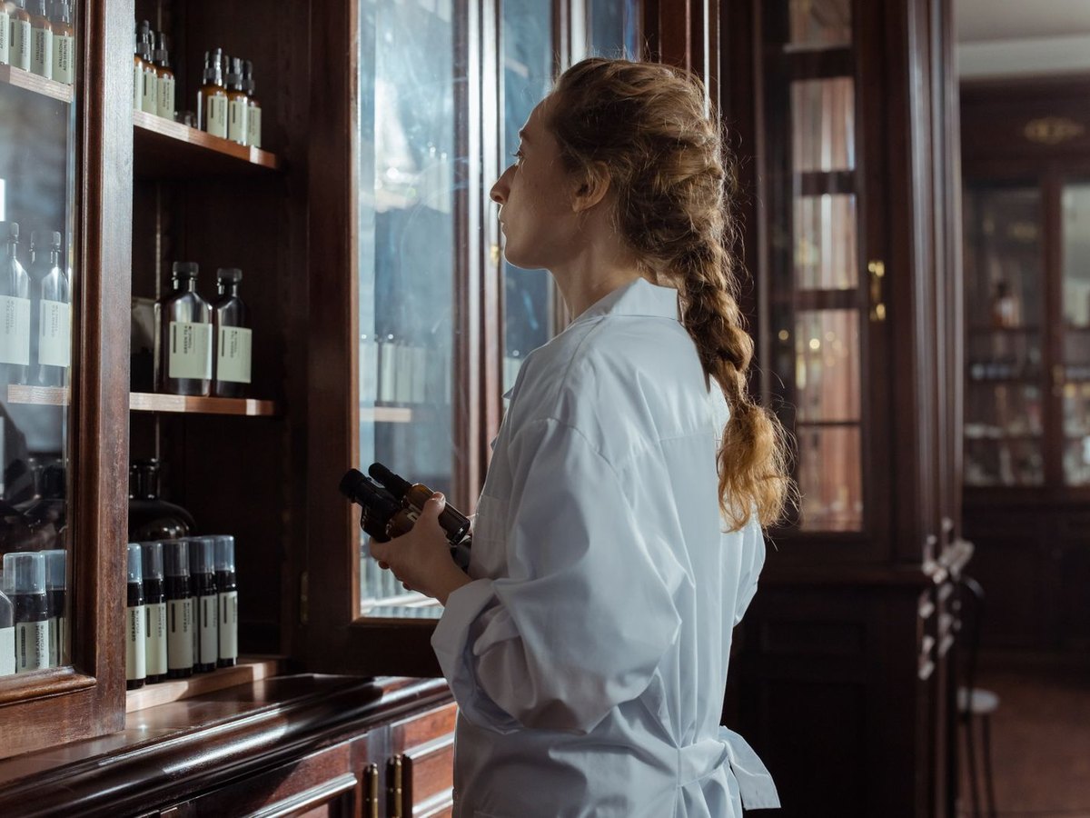 Pharmacist in a white coat inspecting medication bottles in a pharmacy